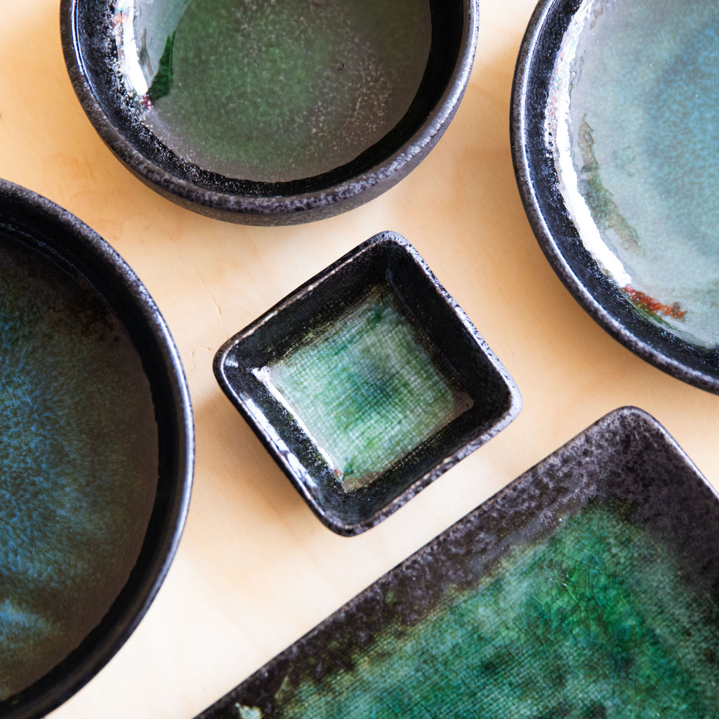 collection of jade and black dishes and high rim plates