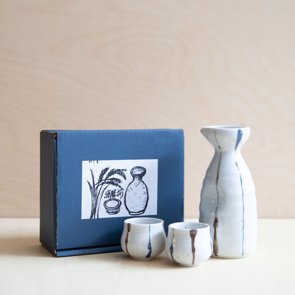 Set of white ceramic sake cups and jug with hand painted vertical lines in blue and brown. This set in made in Japan.