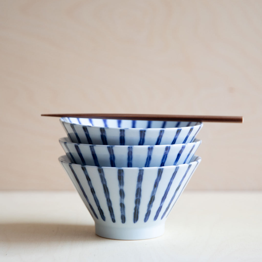 stack of 3 white bowl with blue vertical lines with wooden chopstick