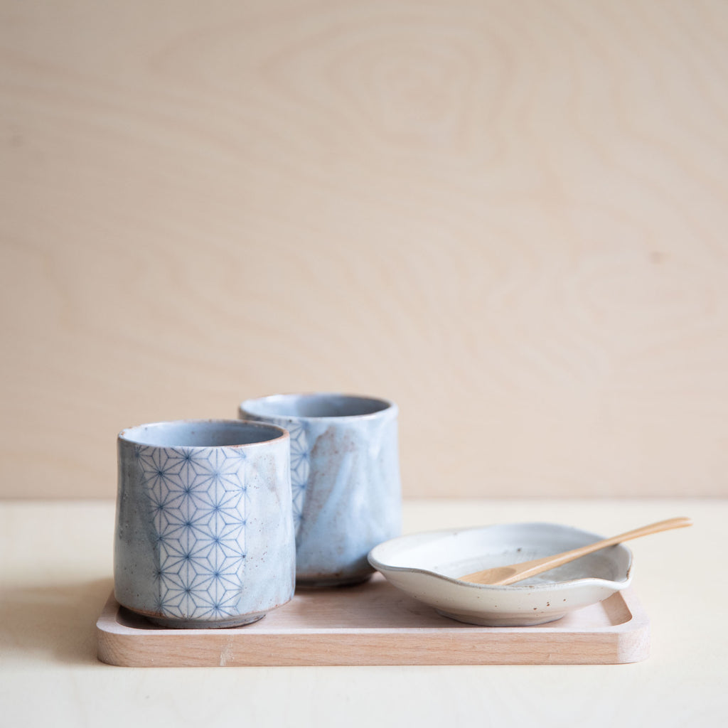 2 grey glazed cup with a patch of asanoha design with a small plate on a wooden tray