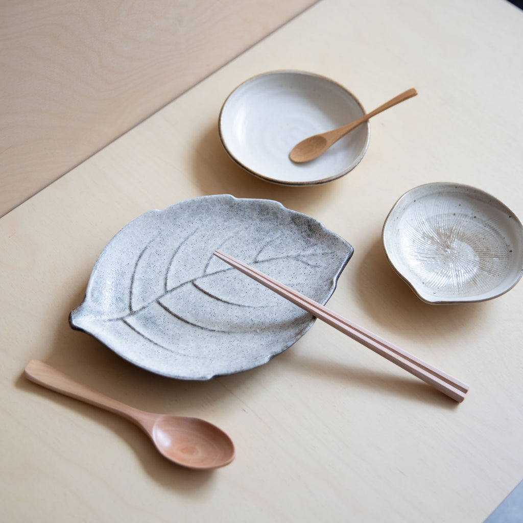 leaf shaped white plate pared with other small dishes and cutlery