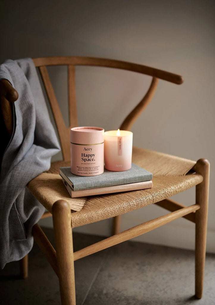 Happy Space Scented Candle - Rose Geranium and Amber on a chair